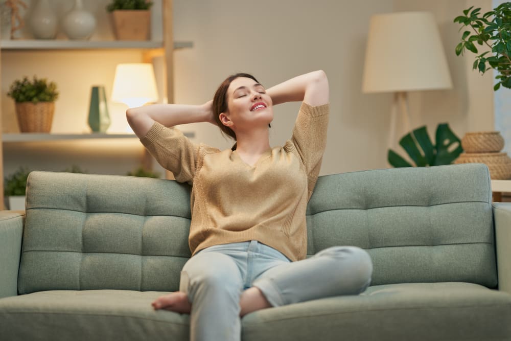 Happy woman sitting on a couch feeling relieved